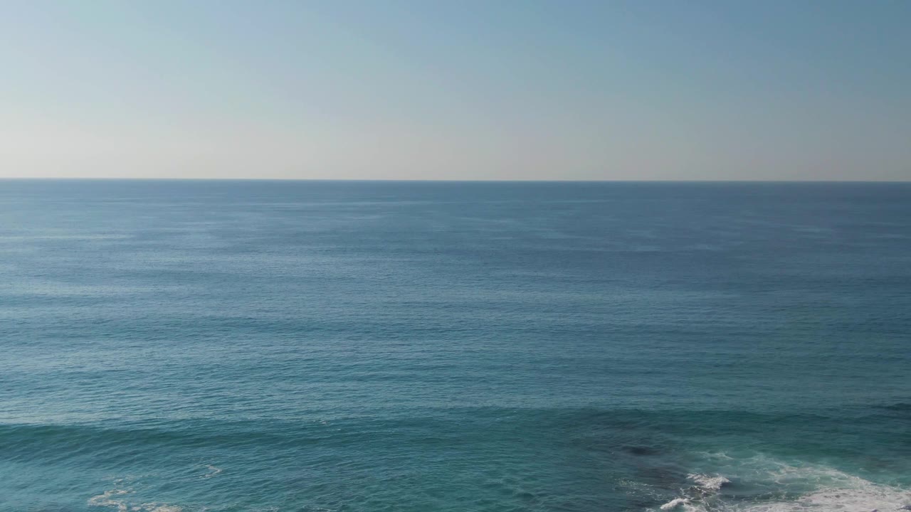 Wide ocean view at Buzzards Beach East Cape BCS Mexico with a level horizon, pale sky, and faint white surf along the lower edge, with no visible people in this frame.