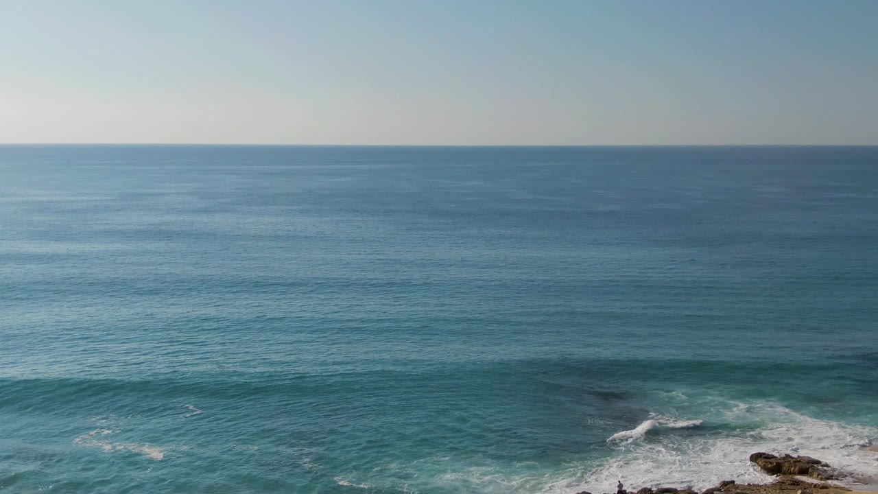 Ocean swells approaching a rocky shoreline at the lower right