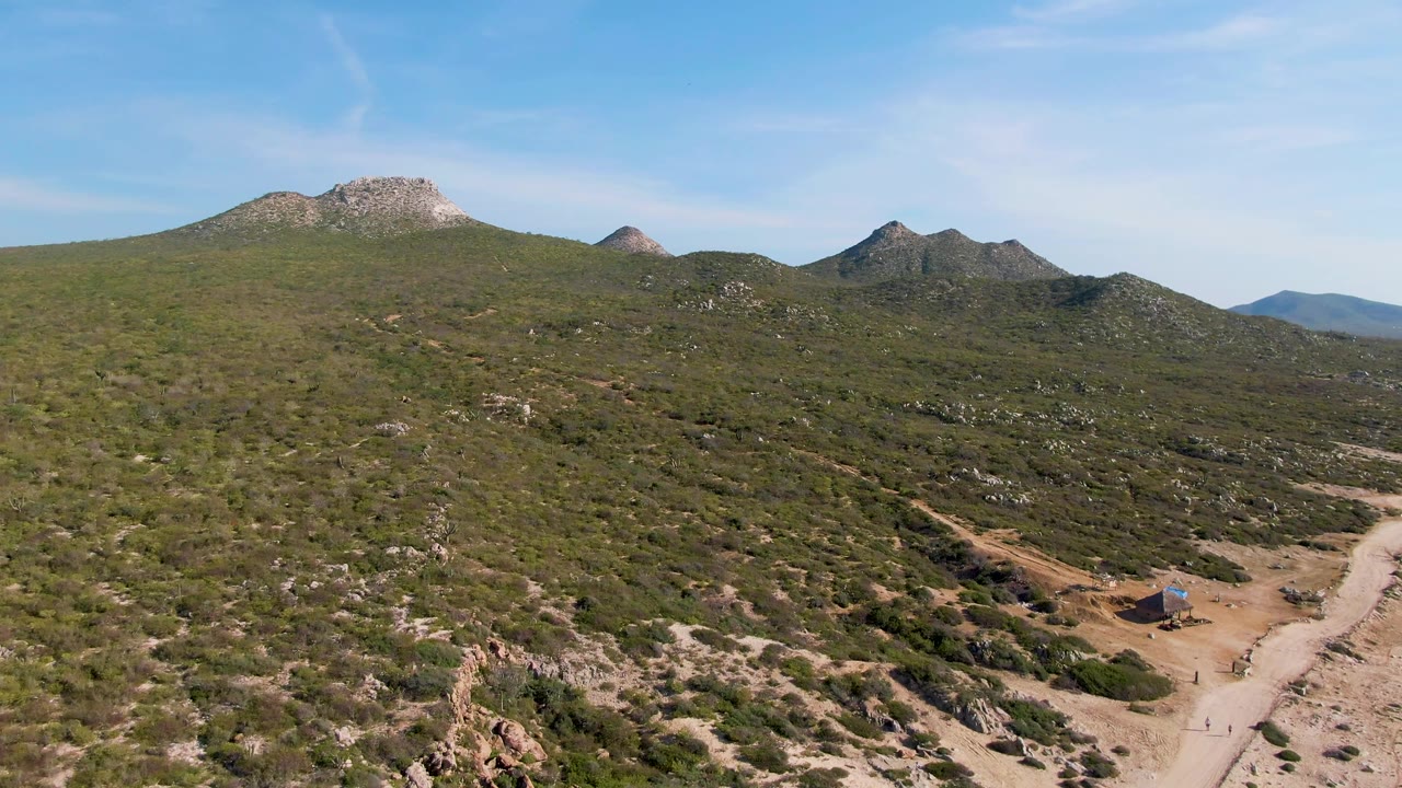 Elevated view of a winding dirt road below rocky green hills.