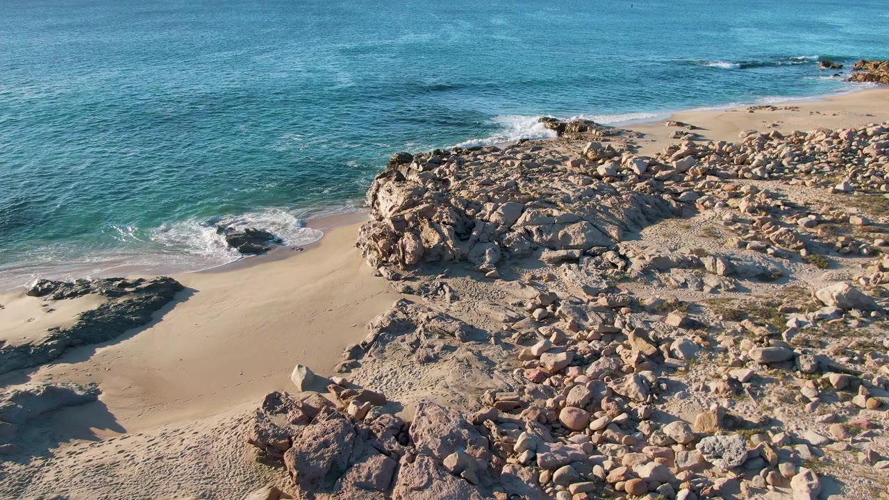 Opening frame at Buzzards Beach East Cape BCS Mexico showing turquoise water, pale sand, rocky outcrops, and no visible people.