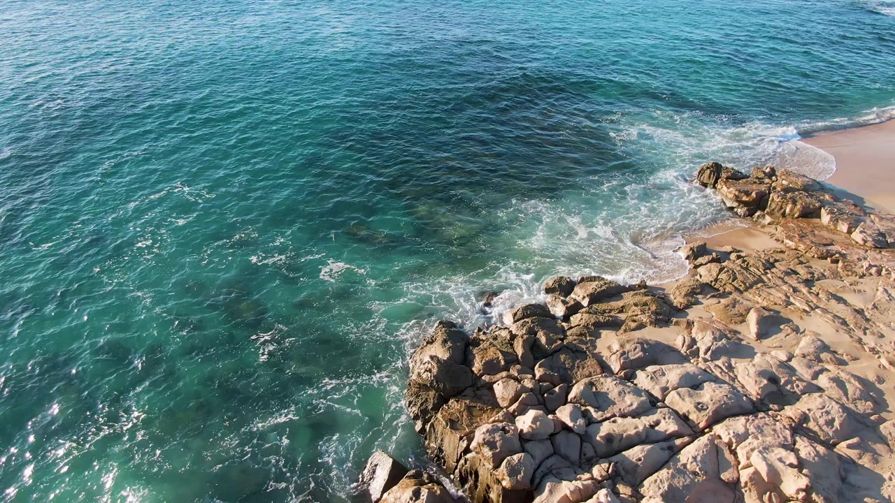 Turquoise ocean washing around pale shoreline rocks