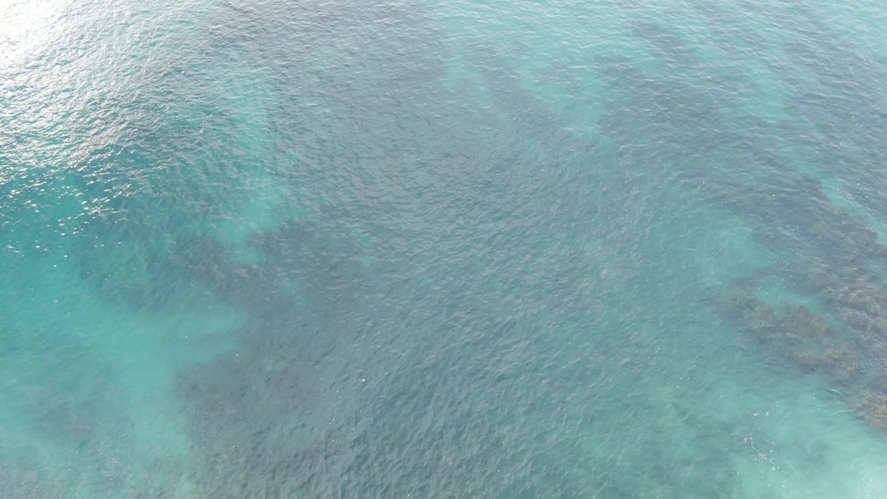 Aerial view of turquoise ocean with submerged reef patches