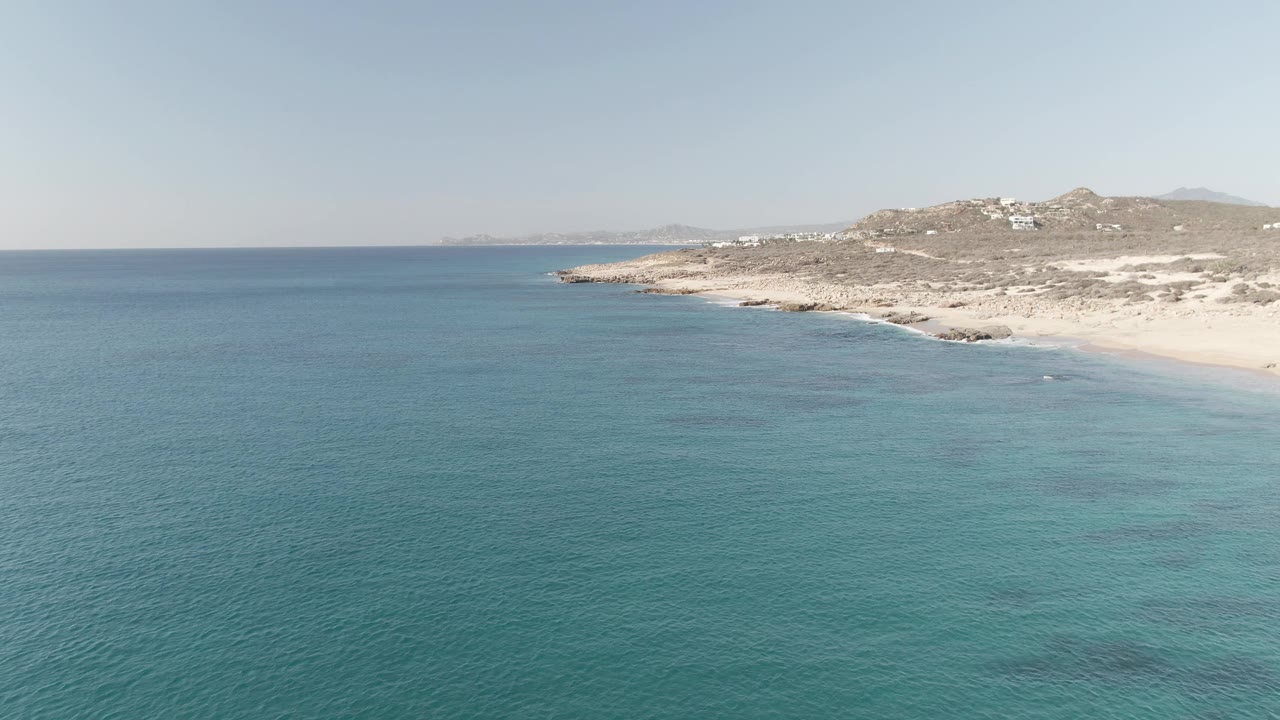 Turquoise ocean beside a sandy beach and rocky headland.