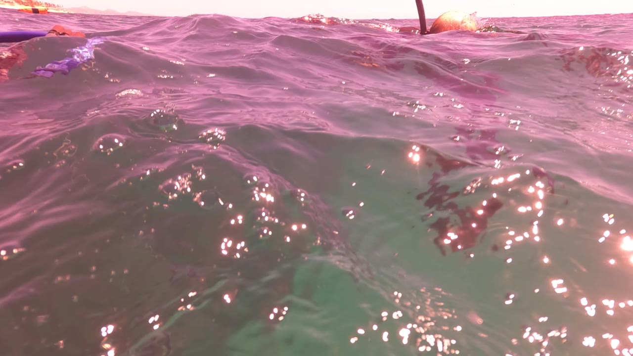 Choppy ocean surface with bright sun glints and a dark protruding line