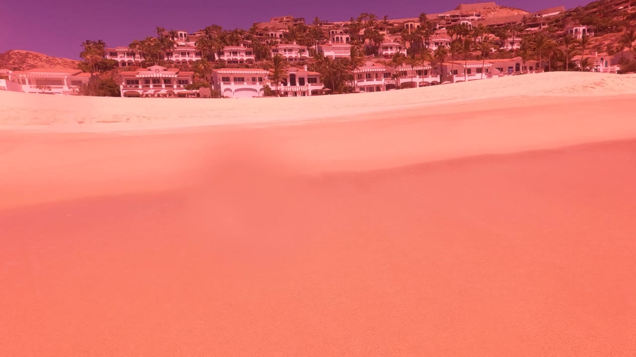 Wide sandy beach with resort buildings and no visible people