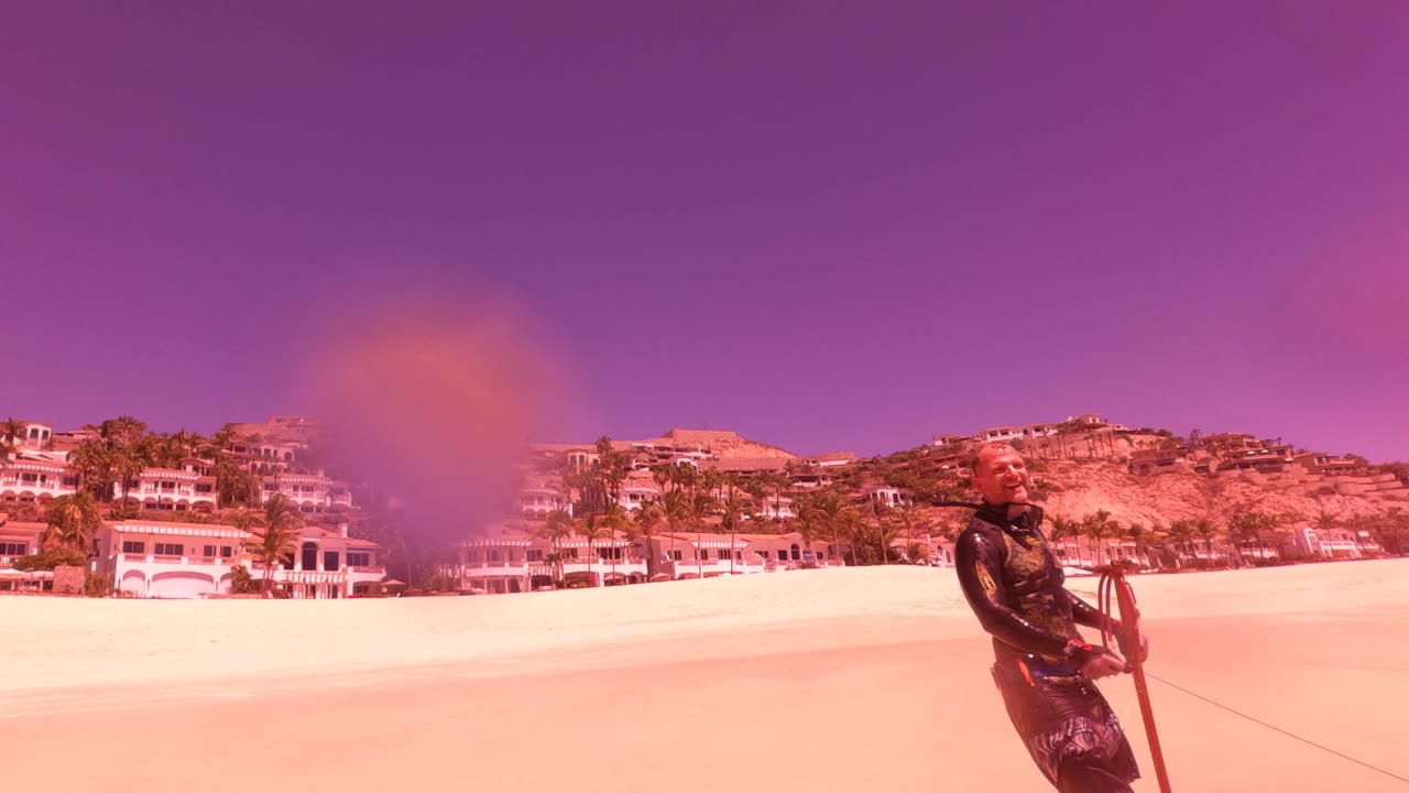 Beach and coastal buildings with fisherman partly visible near the lower right.