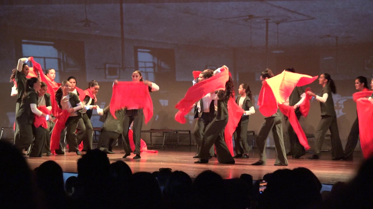 San Jose Del Cabo BCS Mexico stage performance frame showing the ensemble closing toward center as red scarves hang, lift, and wrap around several dancers.