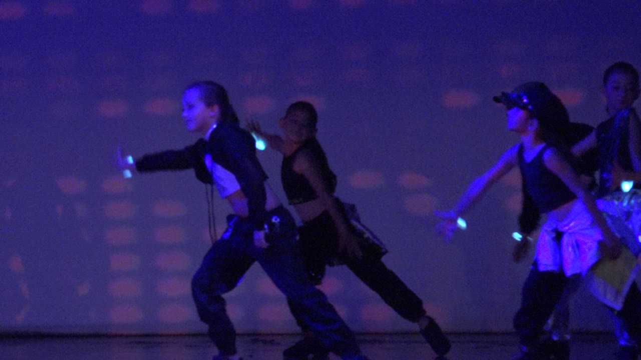 Dancers on the San Jose Del Cabo BCS Mexico stage lean into a choreographed step while glowing wristbands trace small points of blue light.