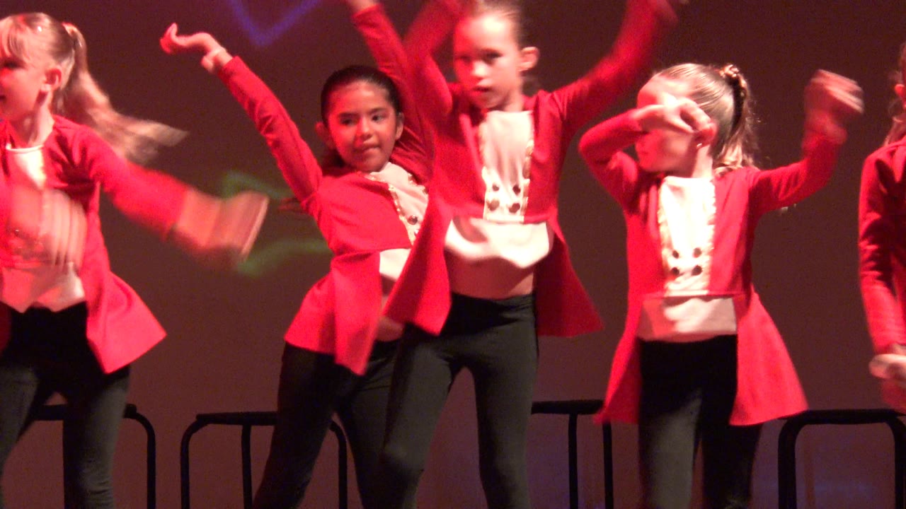 At the start of the San Jose del Cabo BCS Mexico clip, children in red jackets and black pants raise their arms during a stage dance routine under red lighting.