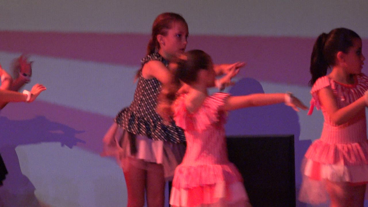Children on stage extending arms during a dance routine