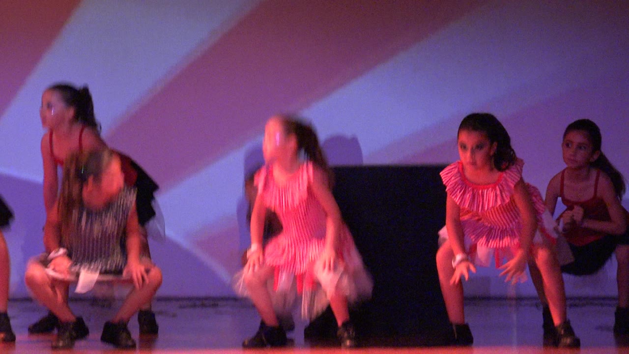 The dancers bend forward and crouch mid-routine on the San Jose Del Cabo BCS Mexico stage, with motion blur visible in the faster movements.