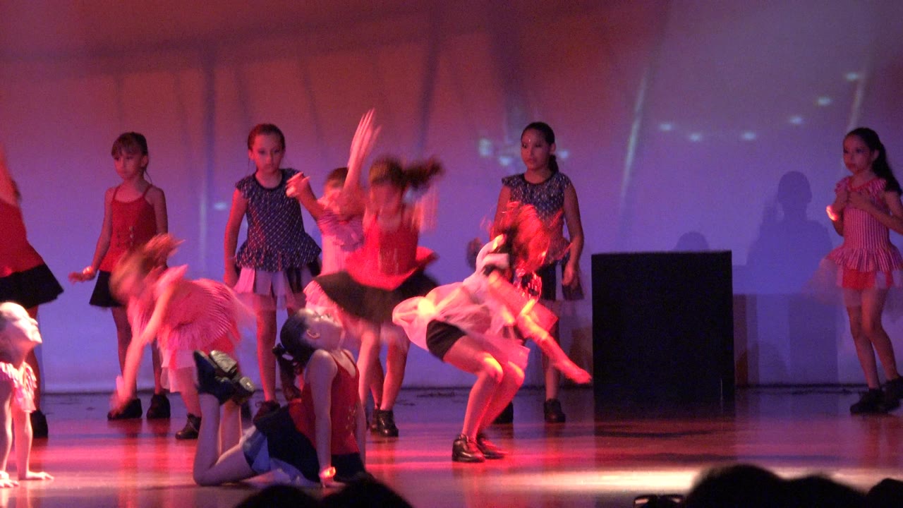 Children continue a stage dance with blurred motion and floor work.