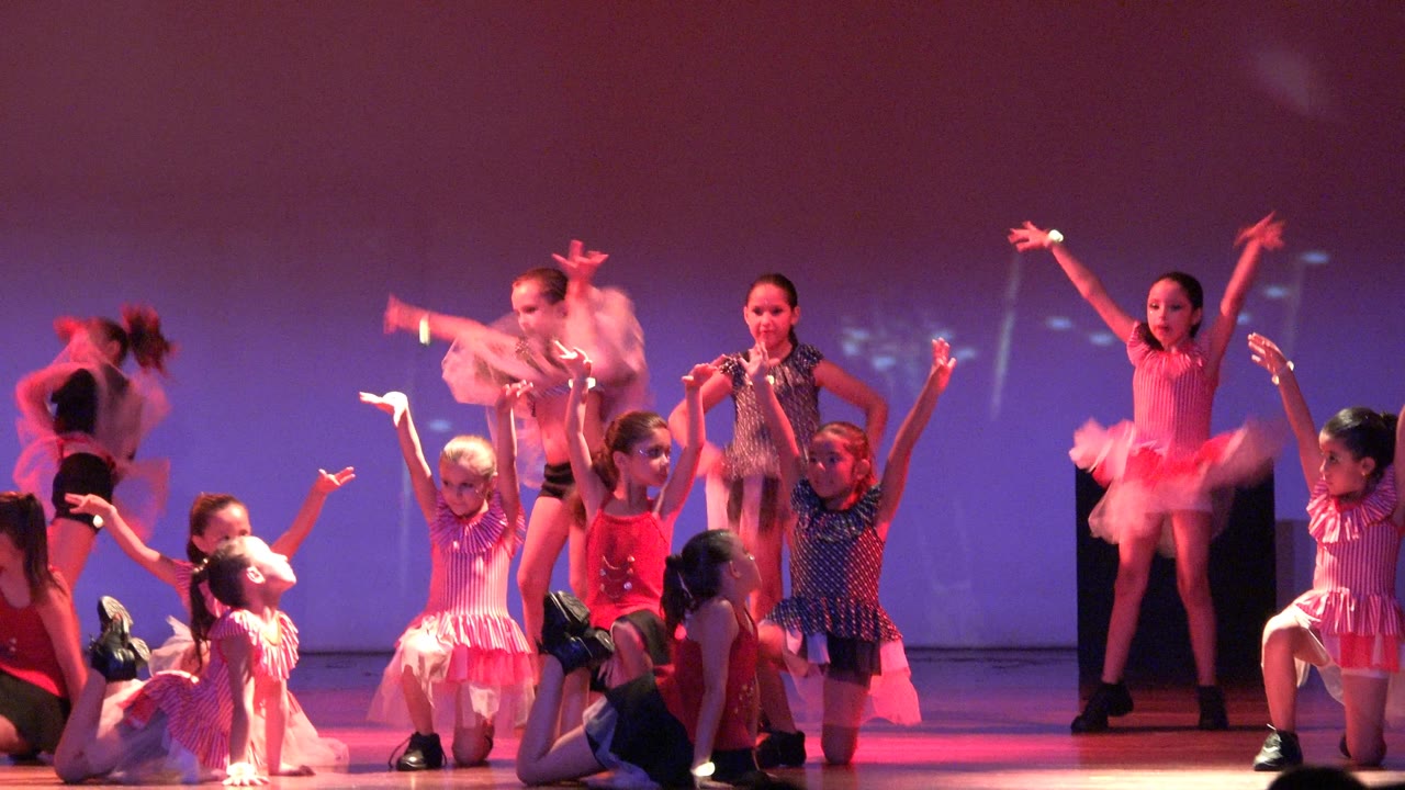 Children in dance costumes shift positions on stage.