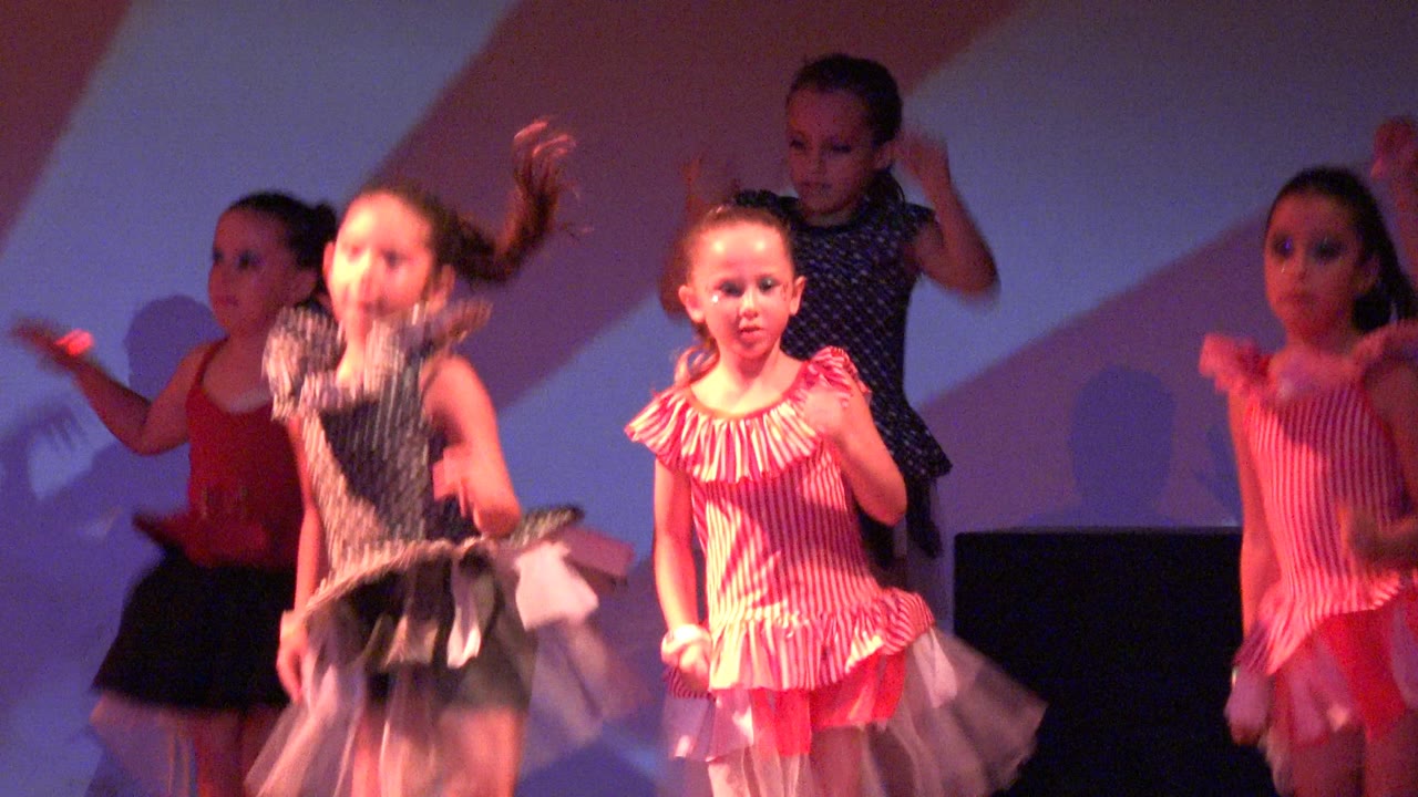 Two girls in pink striped costumes and one in a dark polka-dot costume are prominent during the San Jose del Cabo, Mexico stage performance, with arms and skirts in motion.