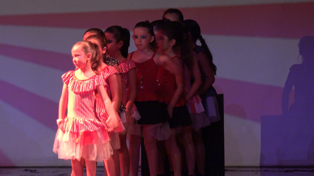 Two young girls in pink striped dresses stand at the front as other children line up behind them on the San Jose Del Cabo BCS Mexico stage.