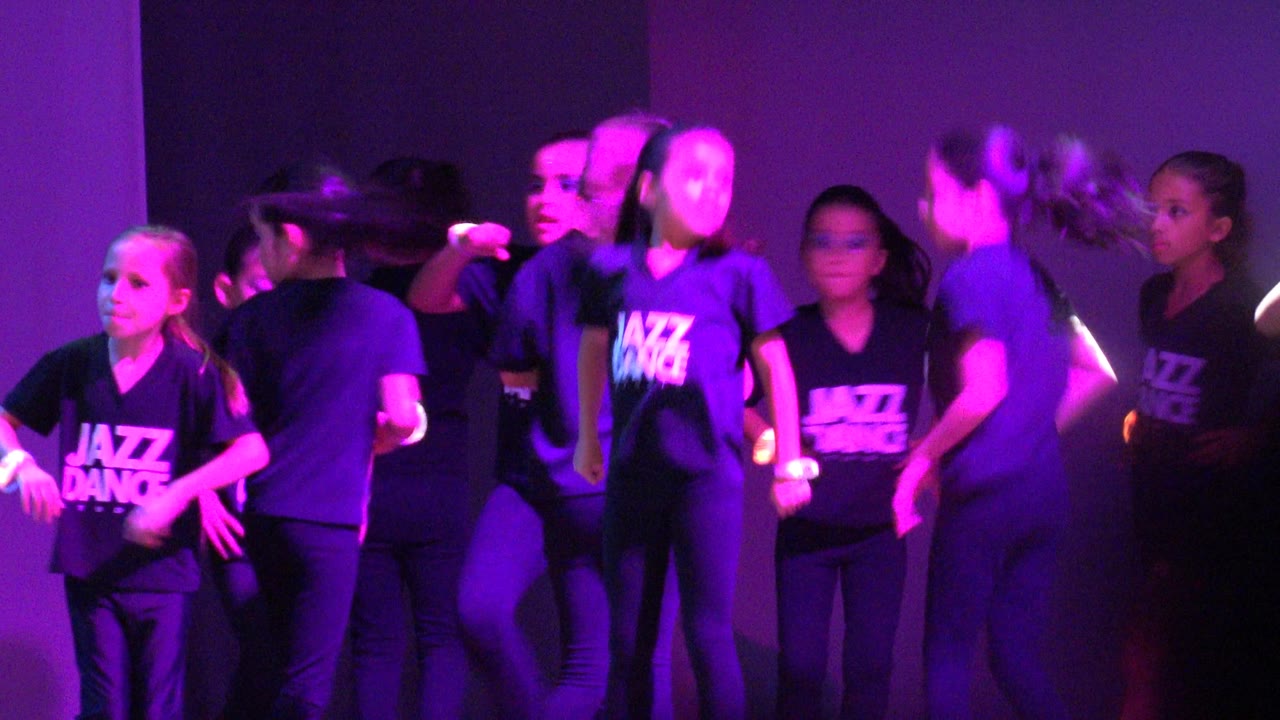 Group of young dancers gathered under purple stage light