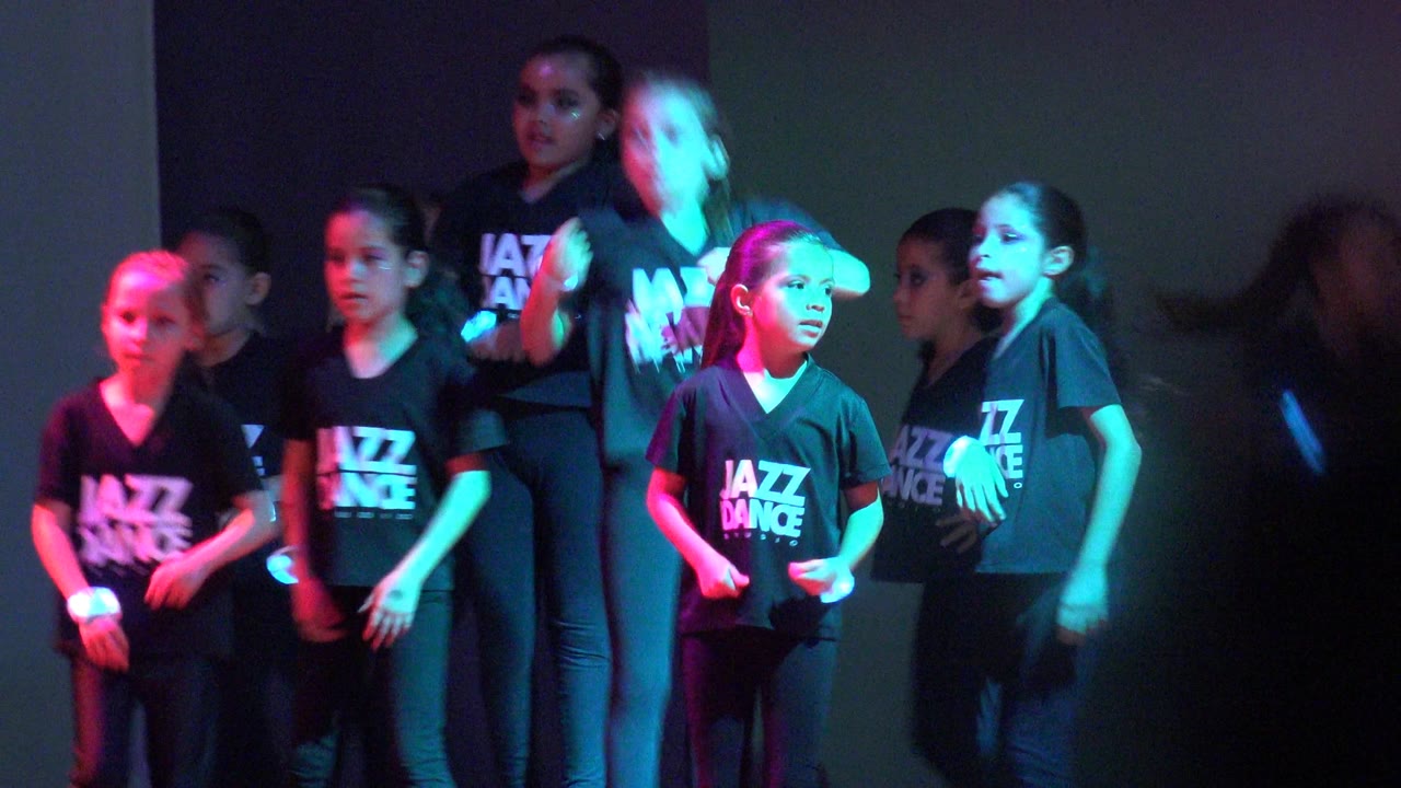 Children in black Jazz Dance shirts continue the routine in San Jose del Cabo BCS Mexico, with cyan light on the front row and magenta light on dancers at the side.