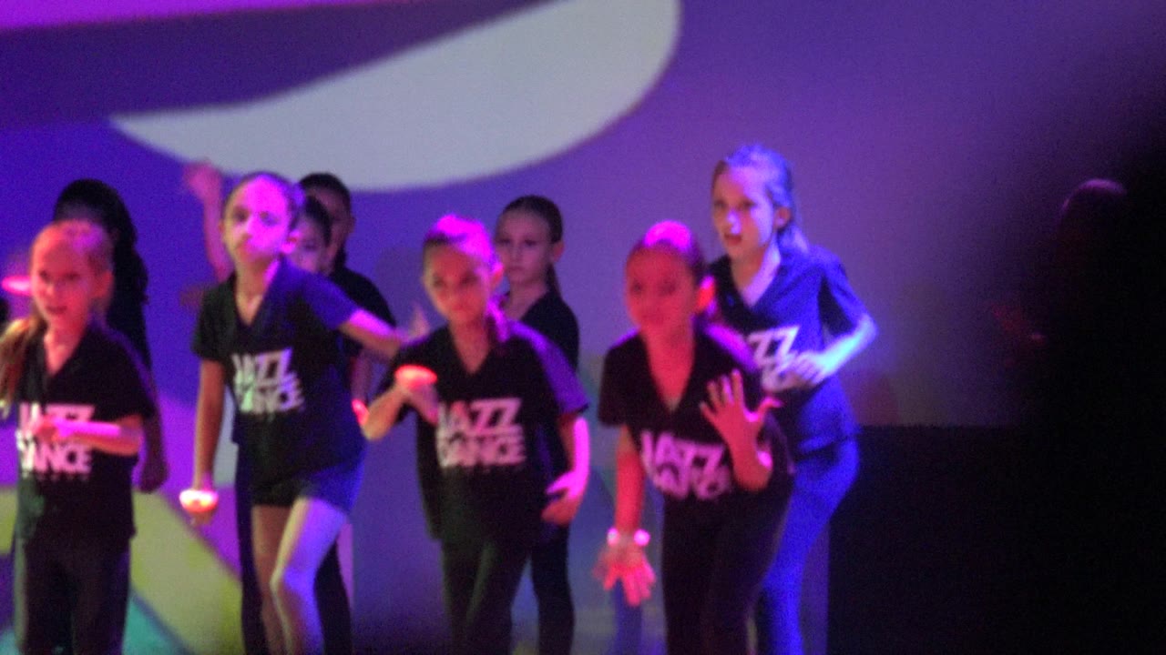 Children continue the choreographed stage performance in San Jose Del Cabo BCS Mexico, with one dancer near the center and others grouped behind under purple and blue light.