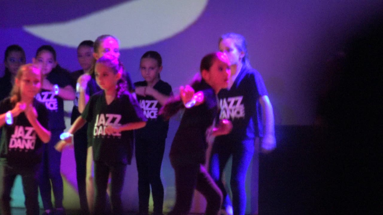 A group of young dancers in San Jose Del Cabo BCS Mexico face different directions during the routine, with purple and pink light across the stage.