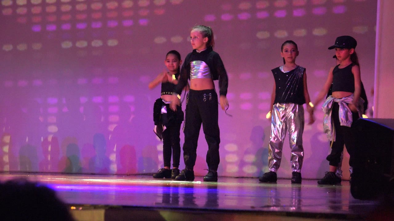 Four children in black and silver performance outfits stand on a San Jose Del Cabo BCS Mexico stage under purple and pink patterned lights at the start of the clip.