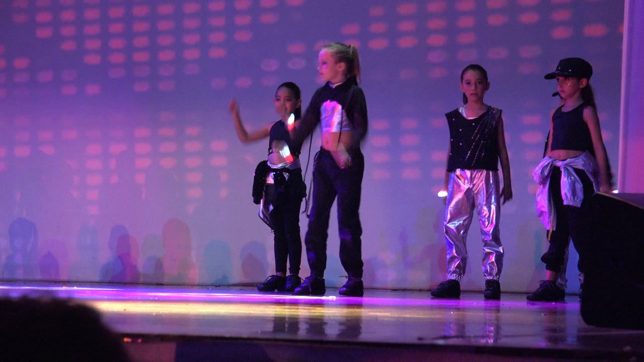 Children on stage as one dancer raises an arm during the routine.