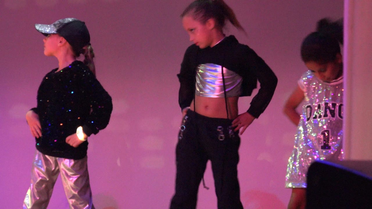 Children hold a hands-on-hips pose on a purple-lit stage in San Jose Del Cabo BCS Mexico, while a dark stage monitor blocks part of the lower right foreground.
