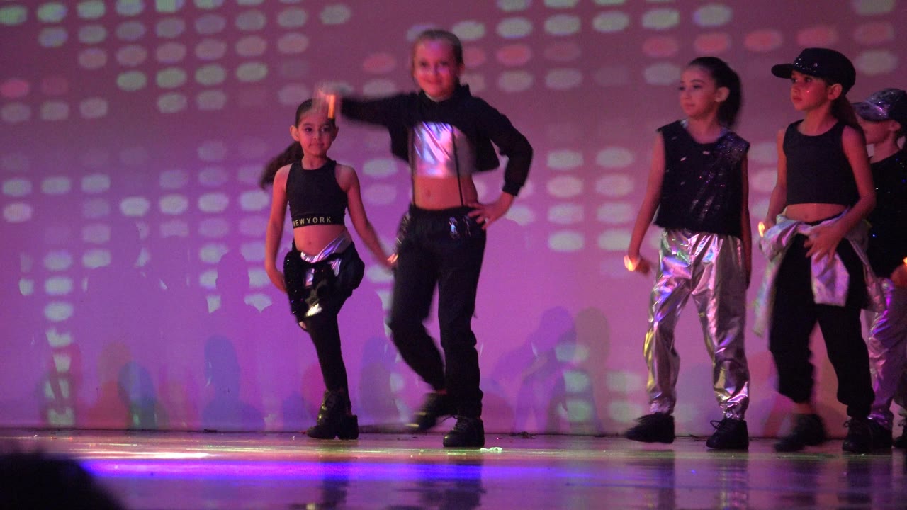 The young dancers move across the stage in San Jose Del Cabo BCS Mexico, with metallic silver pants reflecting pink and purple stage light.