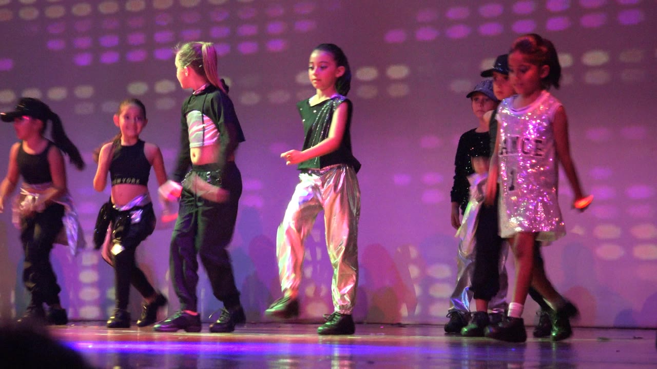 Children perform on a stage in San Jose Del Cabo BCS Mexico, with silver pants, black tops, sequins, and purple lighting across the backdrop.