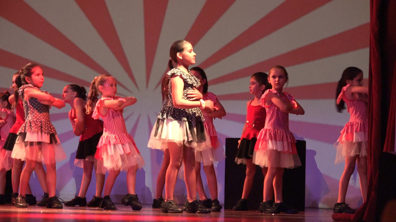 Children perform crossed-arm choreography on stage.