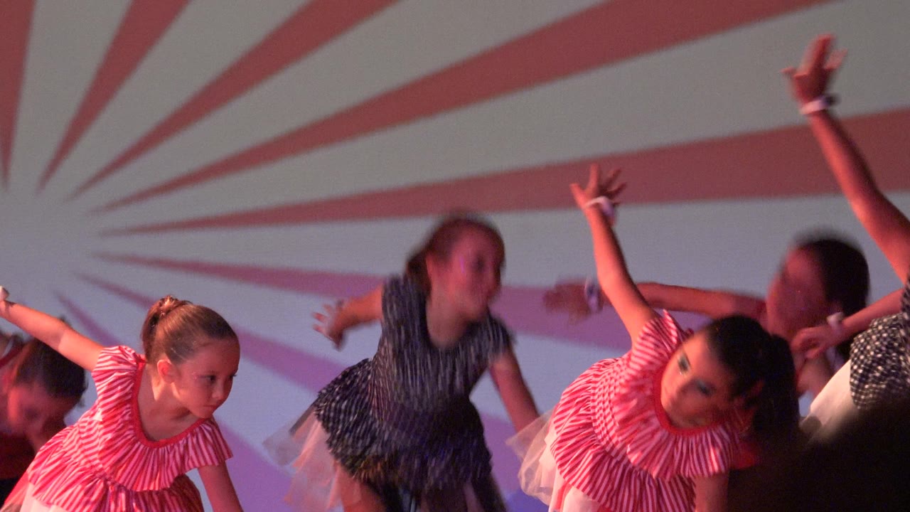 Girls lean and reach during a choreographed stage movement.