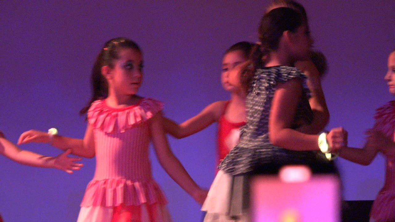 Girls hold hands during a stage dance routine.