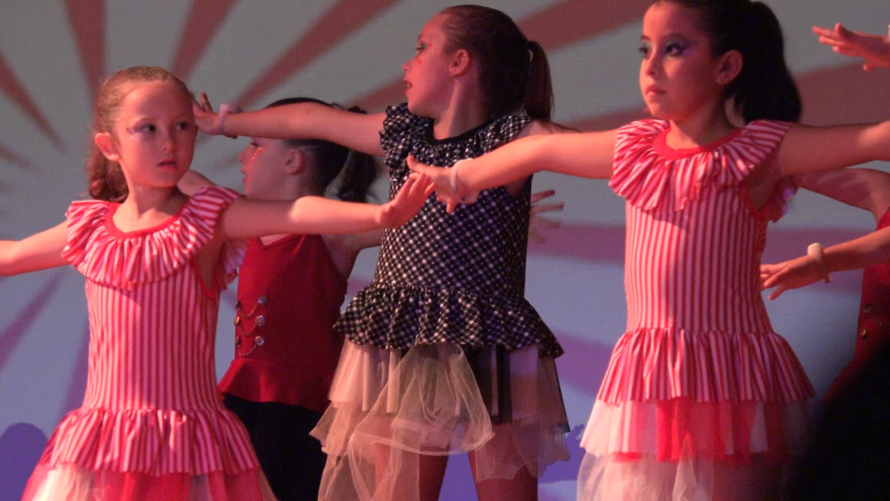 Children extend their arms during a synchronized stage routine.