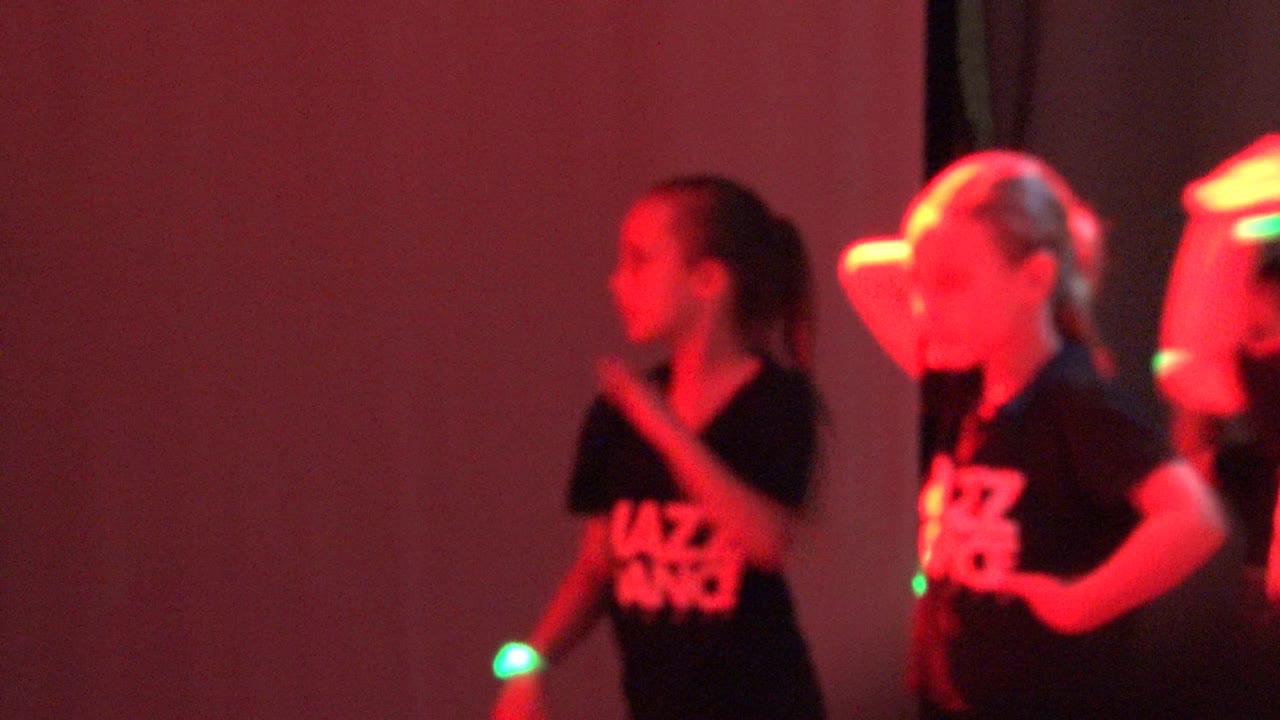 Dance students moving under red light with glow sticks