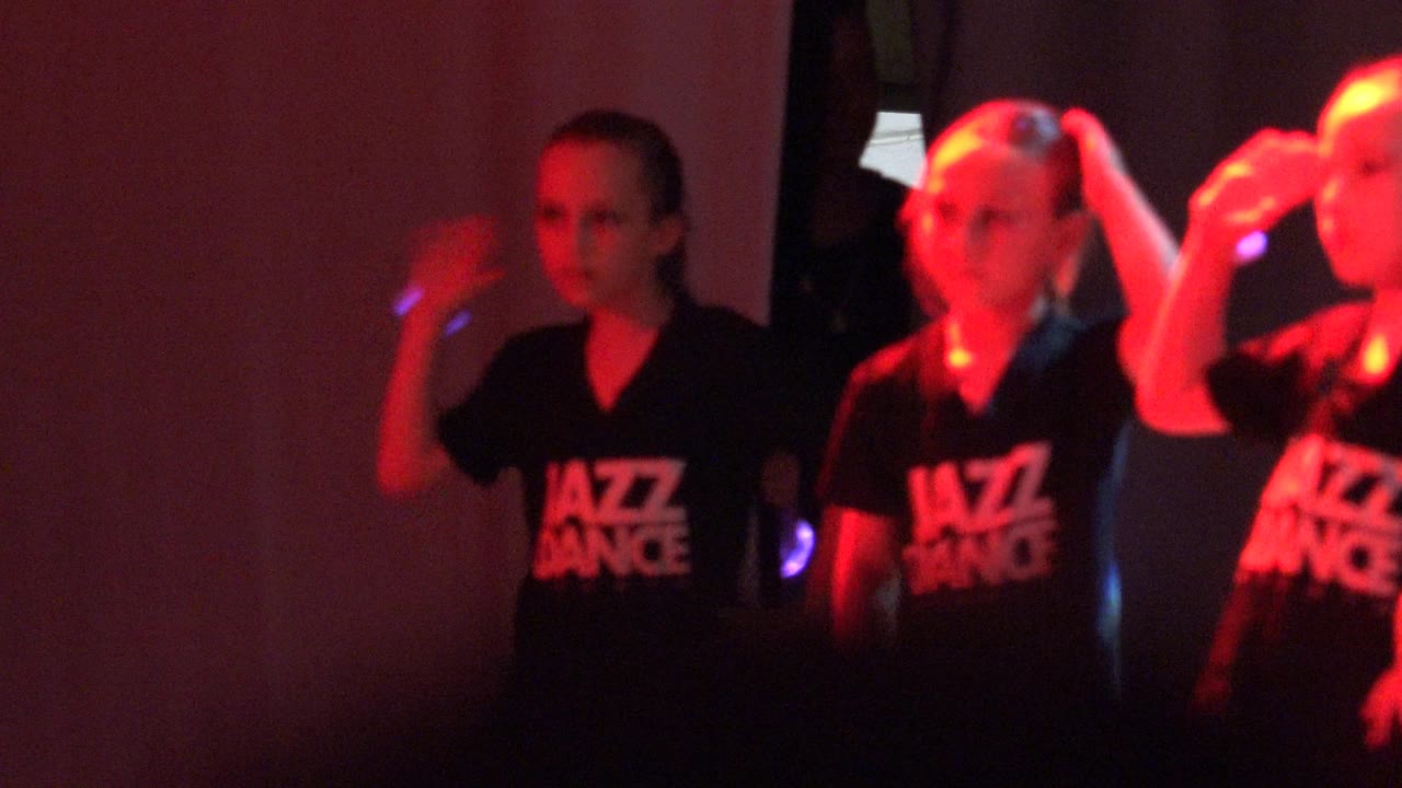 Dance students raising hands in red stage light
