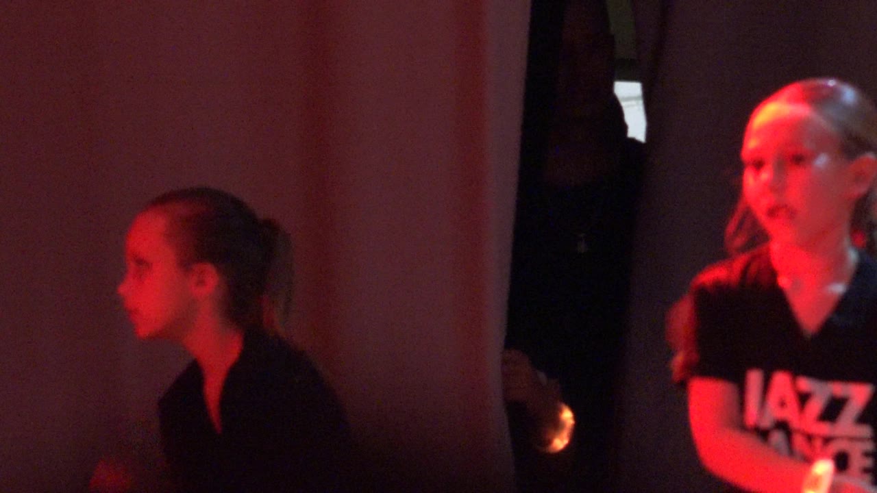 Two children lit by red glow in a dark room.
