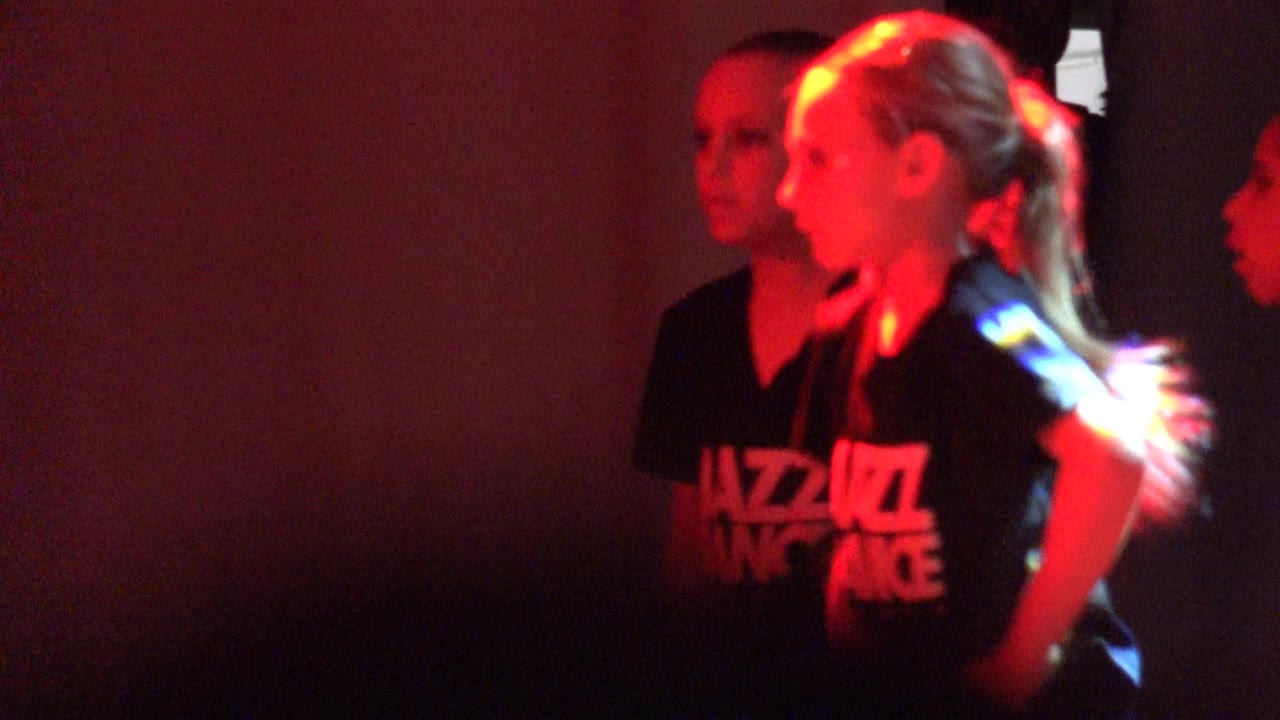 Young dancers in black shirts lit by red stage light
