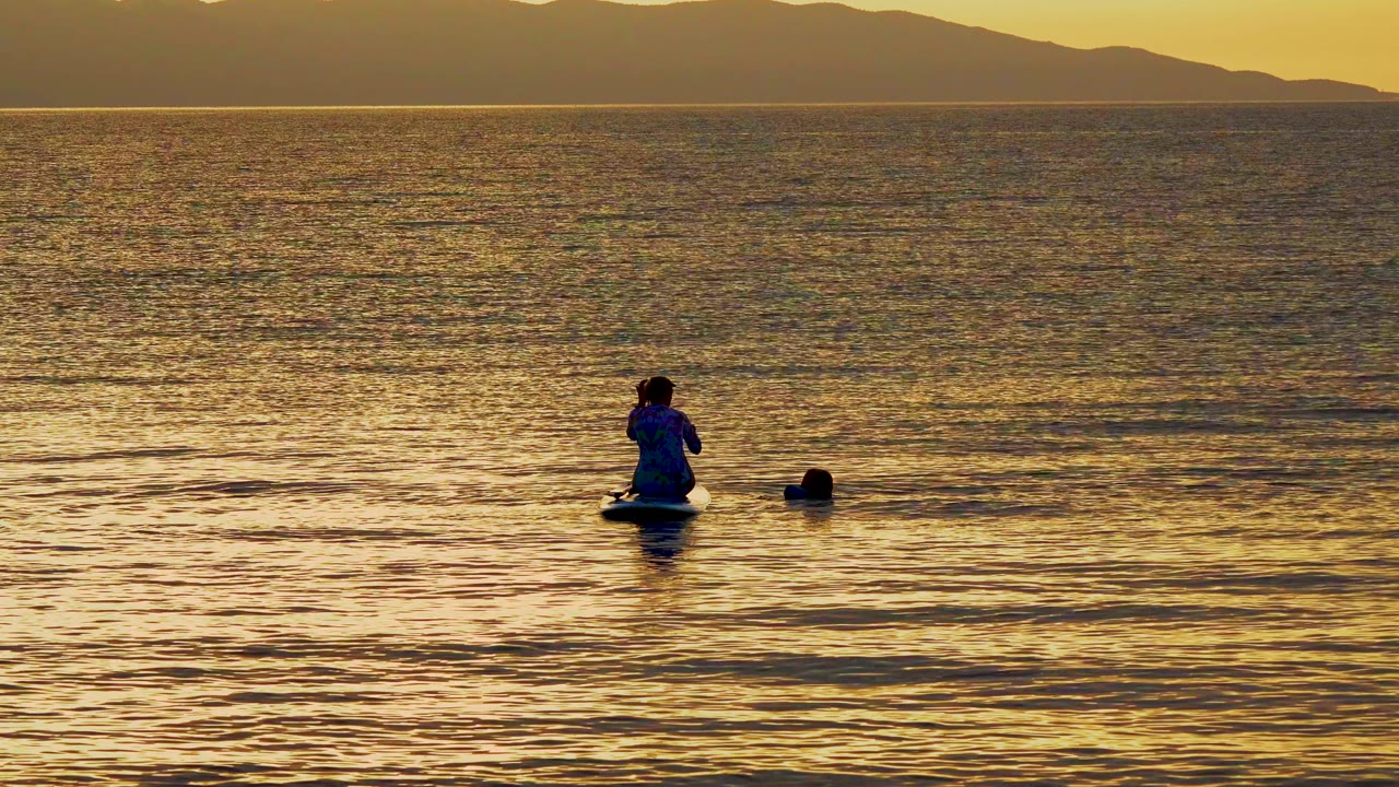 Person on a float turned slightly on calm sunset water
