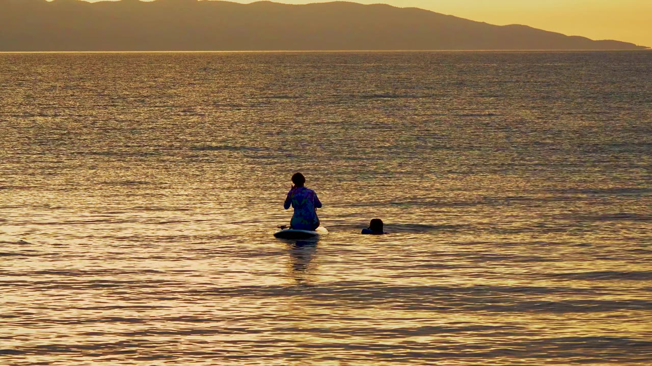 At El Sargento La Ventana Mexico, the paddleboarder is slightly right of center with the swimmer nearby and a long band of warm light across the water.
