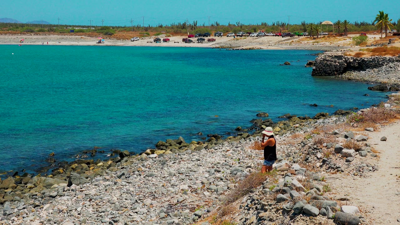 Person standing near rocks and clear shoreline water