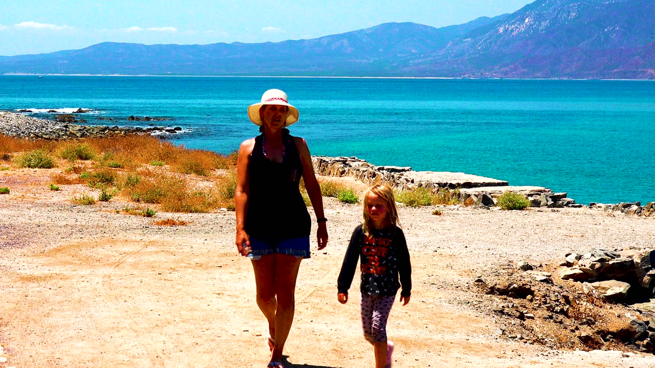 Woman and child continue forward on a coastal dirt path.