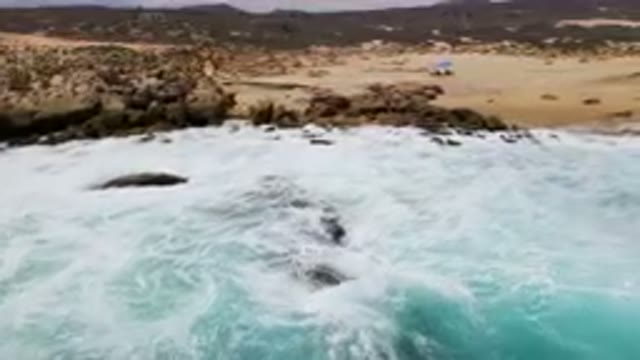 LAGUNA BEACH EAST CAPE BCS MEXICO-2023: Surfers Riding Waves on a Rocky Shoreline