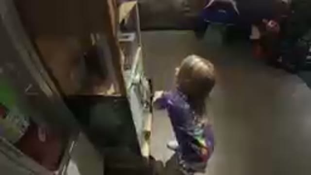 Girl In Purple Shirt Standing In Kitchen With Open Refrigerator
