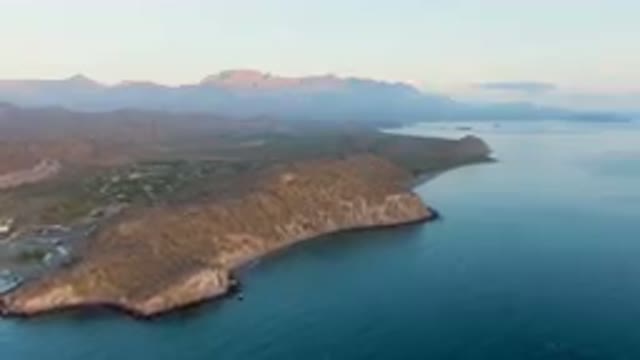 DANZANTE BAY LORETO BCS MEXICO-2023: Mountains And A Body Of Water With A Small Shoreline