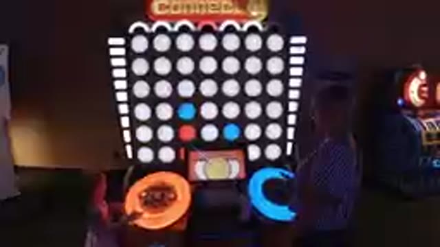 Two People Playing A Game With A Large Screen