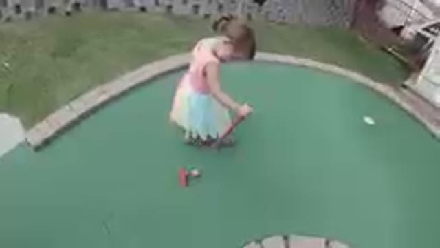 Cute Little Girl Dragging a Golf Ball to a Hole