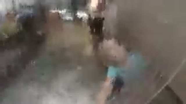 Man Standing In A Water Fountain With A Blue Shirt