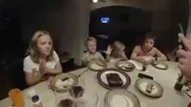 A Lot Of Children Sitting At A Table Eating Cake