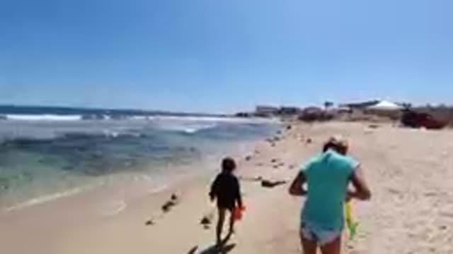 CABO BAJA CALIFORNIA SUR MEXICO-2019: Woman And Child Running Along Sandy Beach