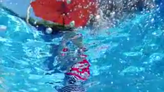 CABO BAJA CALIFORNIA SUR MEXICO-2019: Underwater View Of Person Jumping Into Poolside With Red Umbrella