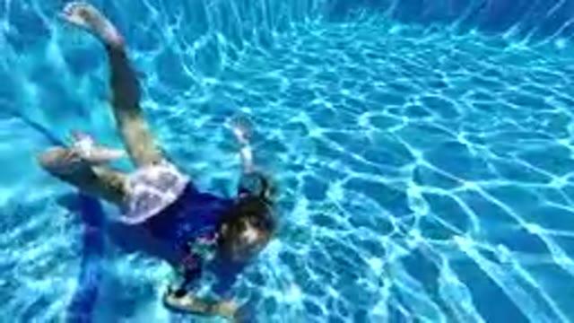 Young Girl Swimming In A Pool With A Blue Background